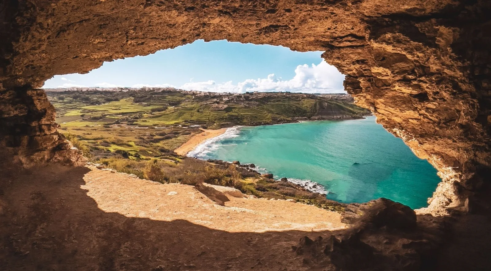 View of Ramla Bay and its red sand beach framed by the mouth of Tal-Mixta Cave on Gozo