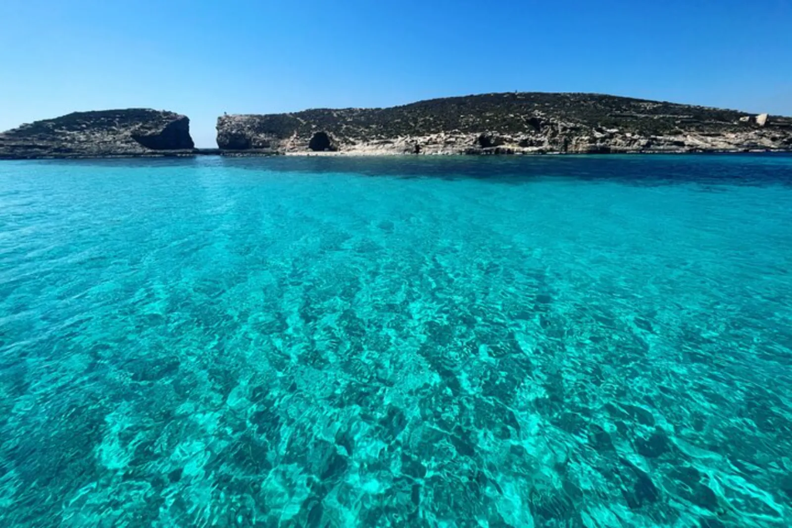 Clear turquoise water at the Blue Lagoon with Comino's coast beyond