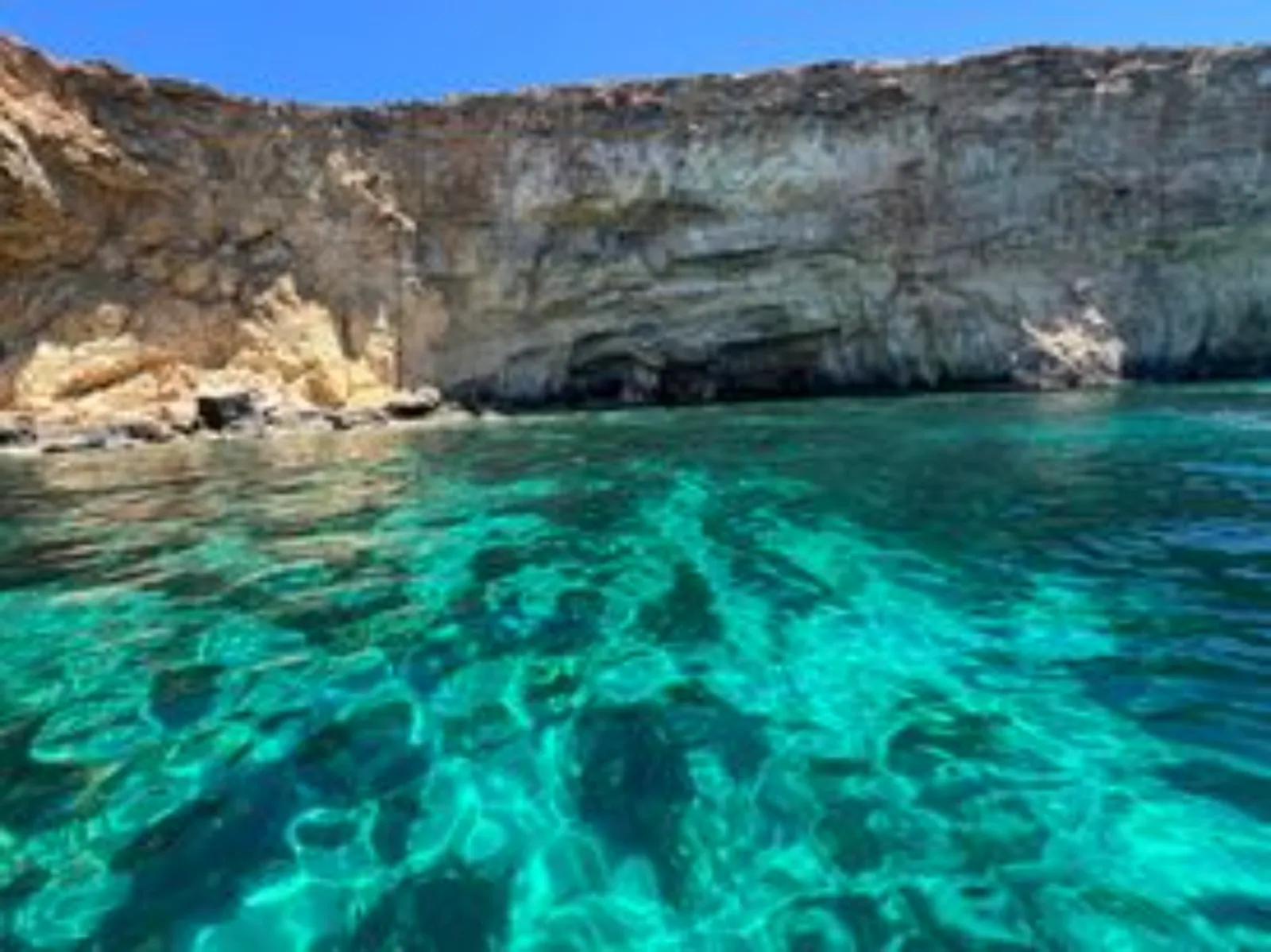 Inside a Comino sea cave, with sunlight through the clear water below