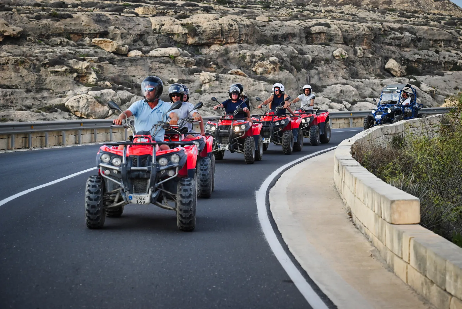 Group of quad bikes riding in convoy along a Gozo coast road
