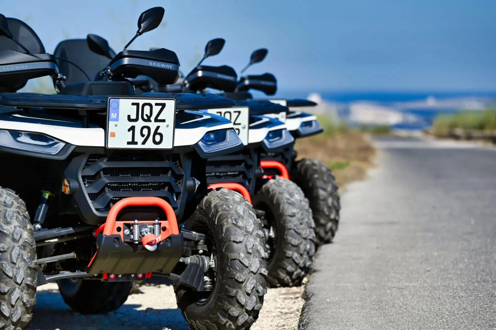 Two rental quad bikes on a coast road on Gozo with the sea behind