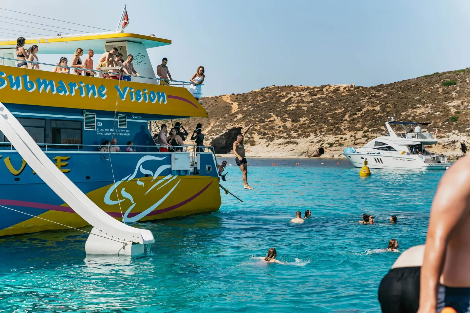 Swimmers and a boat waterslide in the Blue Lagoon on a Gozo and Comino day trip