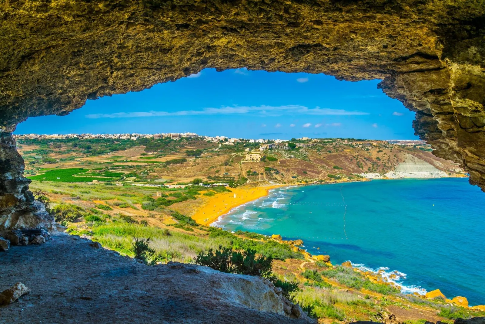 View out of a cave mouth over a Gozo bay and its green headland