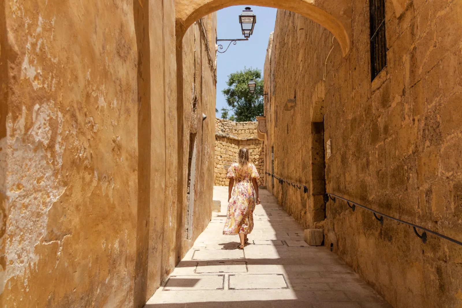 Visitor walking a narrow limestone lane in Victoria on Gozo