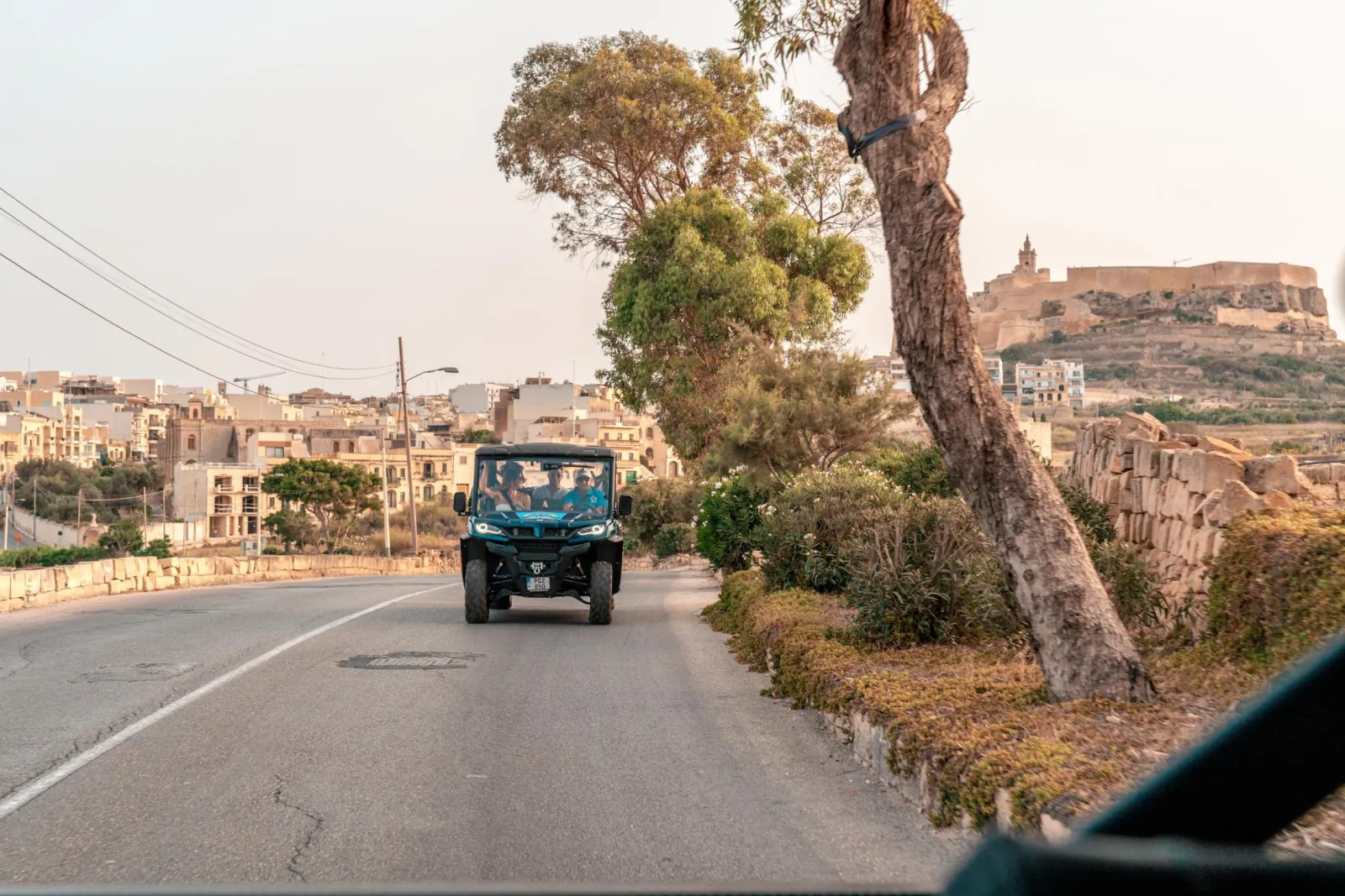 Tour jeep on a country road heading toward a hilltop village on Gozo