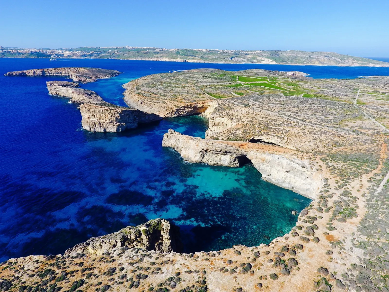 Aerial view of Comino's rocky coast and the deep blue water around it