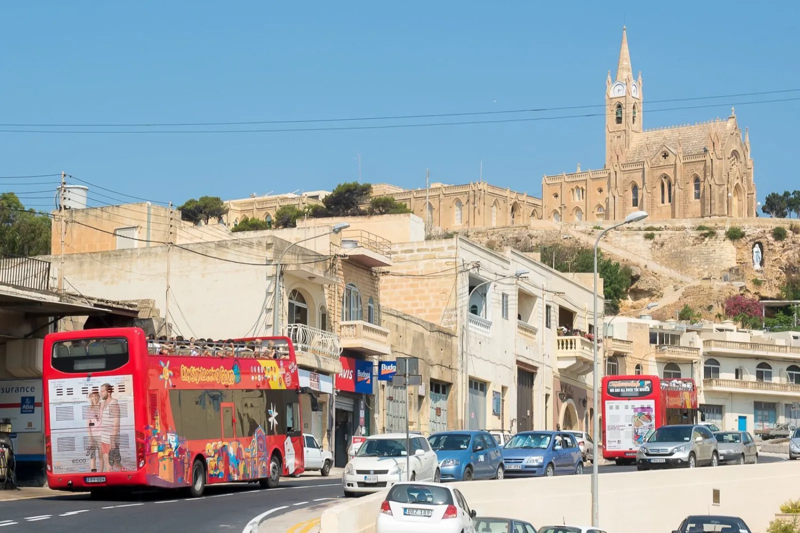 Gozo hop-on hop-off bus on a village street below a church