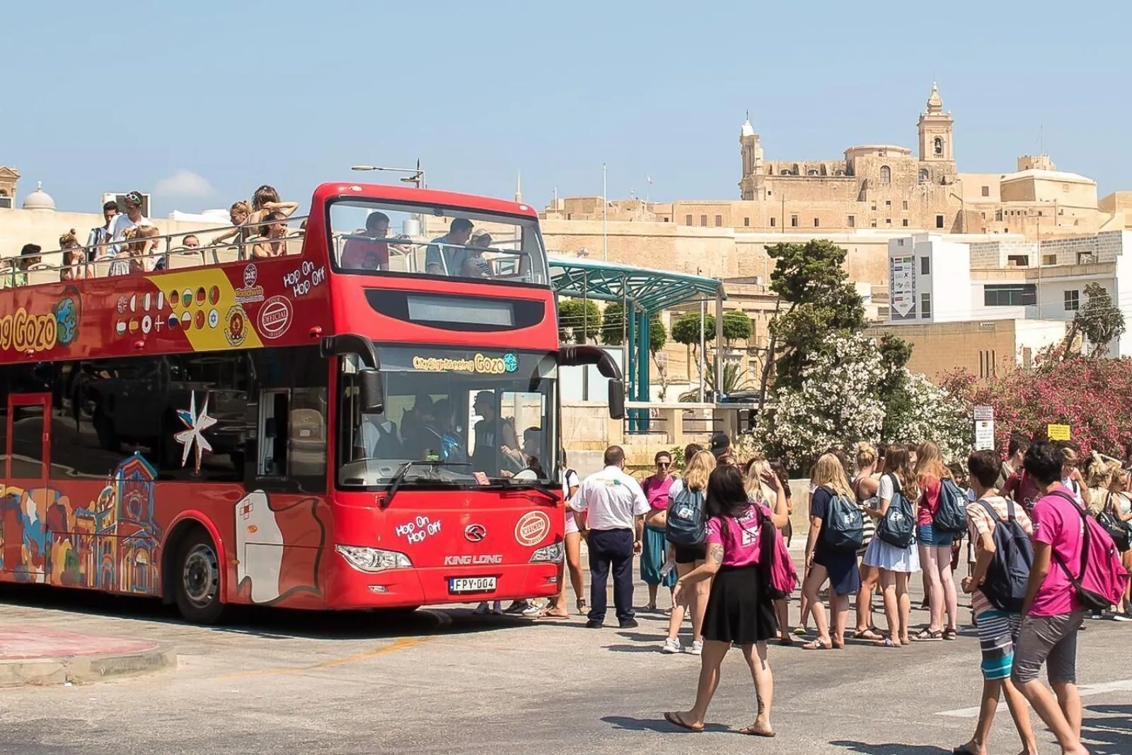 Passengers boarding the Gozo sightseeing bus below the Citadel walls