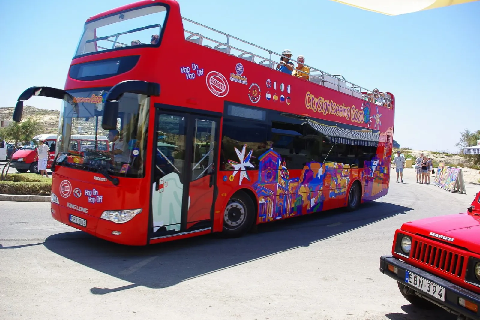 Two City Sightseeing Gozo open-top buses at a stop on the island loop