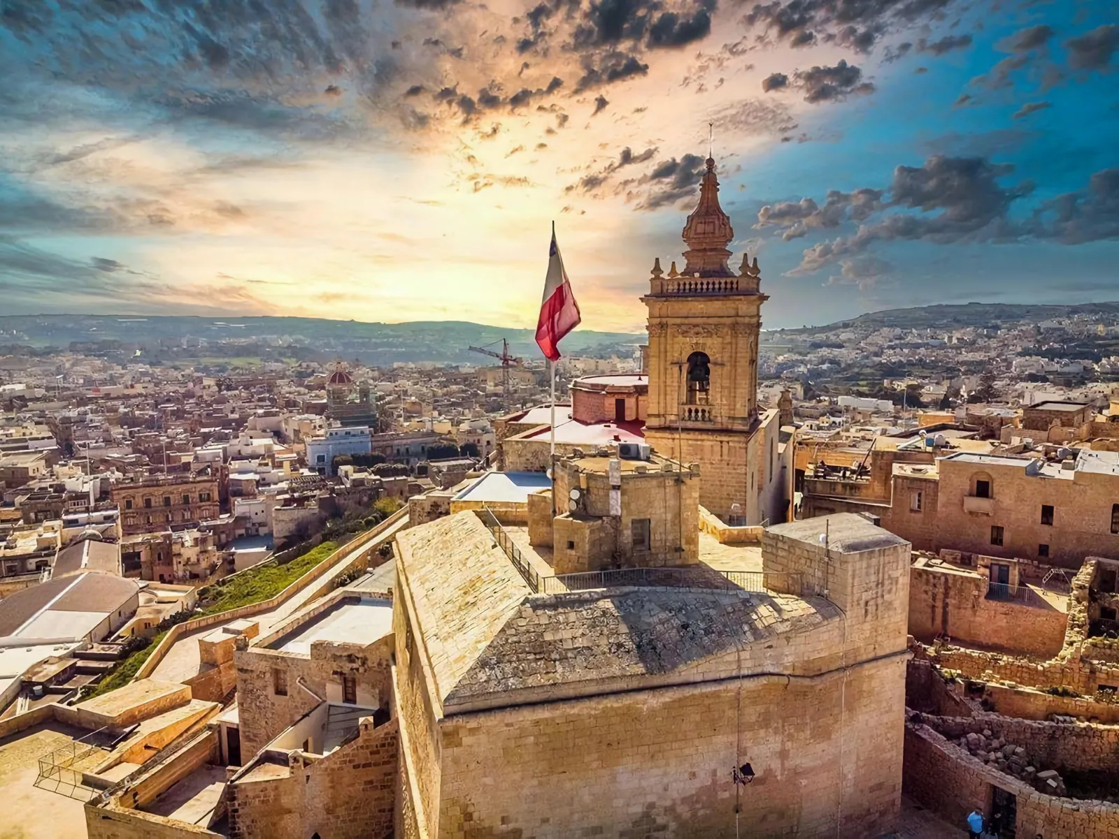 The Cittadella above Victoria on Gozo at sunset with the Maltese flag flying
