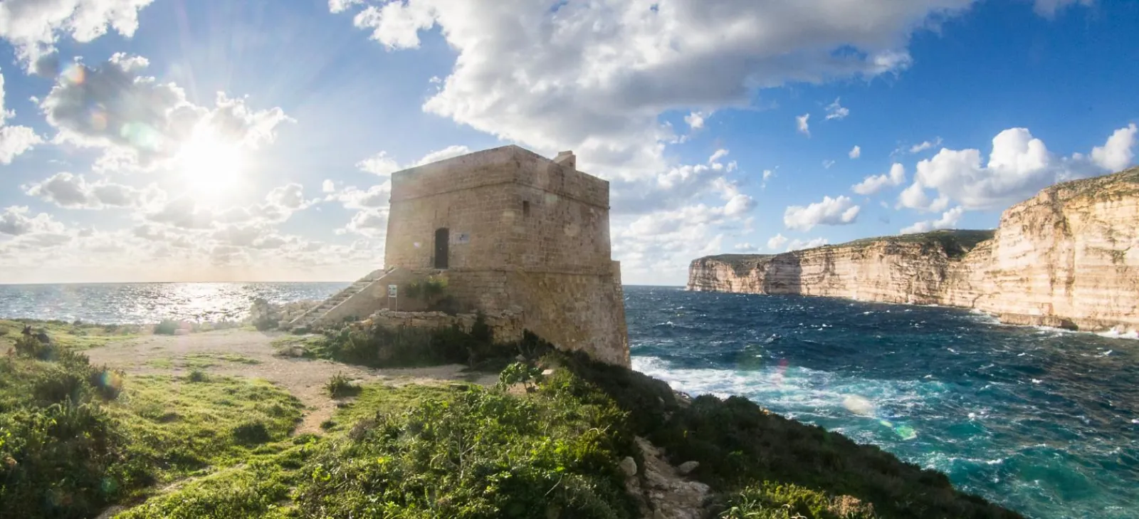 Coastal watchtower on the Gozo cliffs with the sun low over the sea