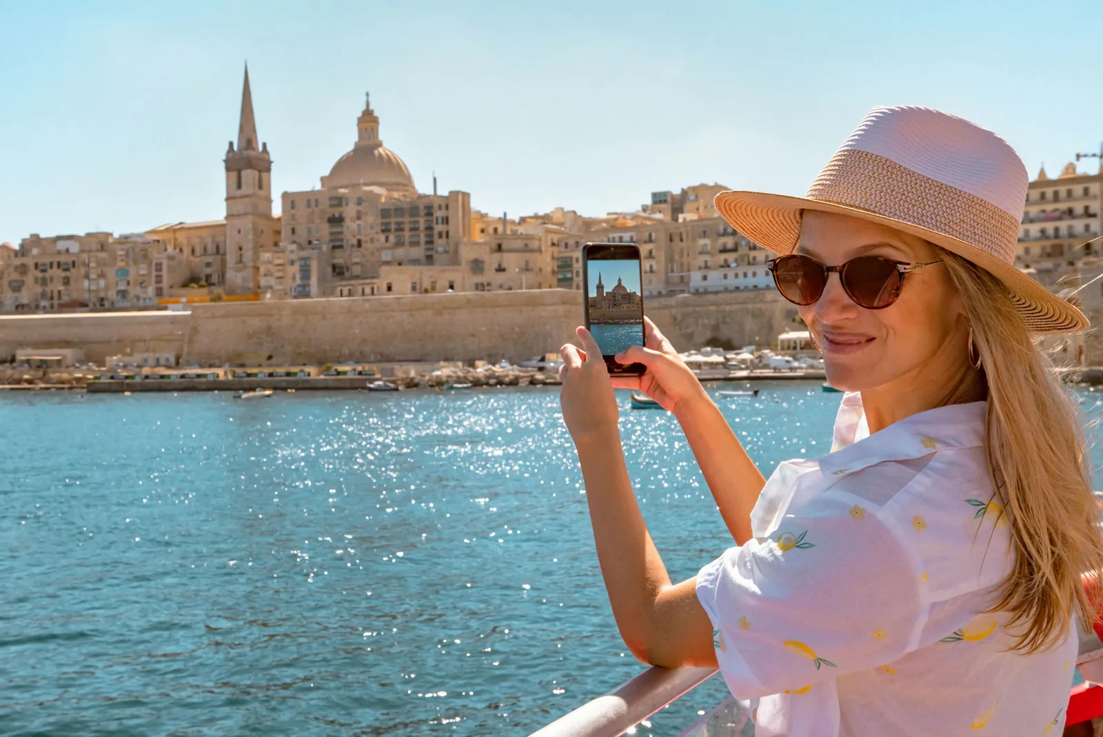 Passenger photographing Valletta's skyline from the deck of a Gozo ferry cruise