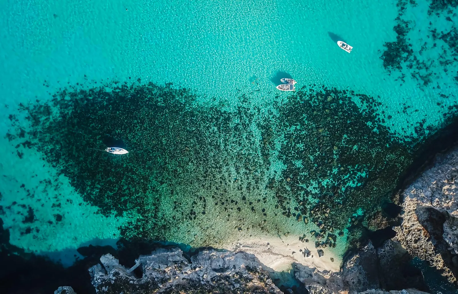 Aerial view of turquoise water against the cliffs on the Comino coast