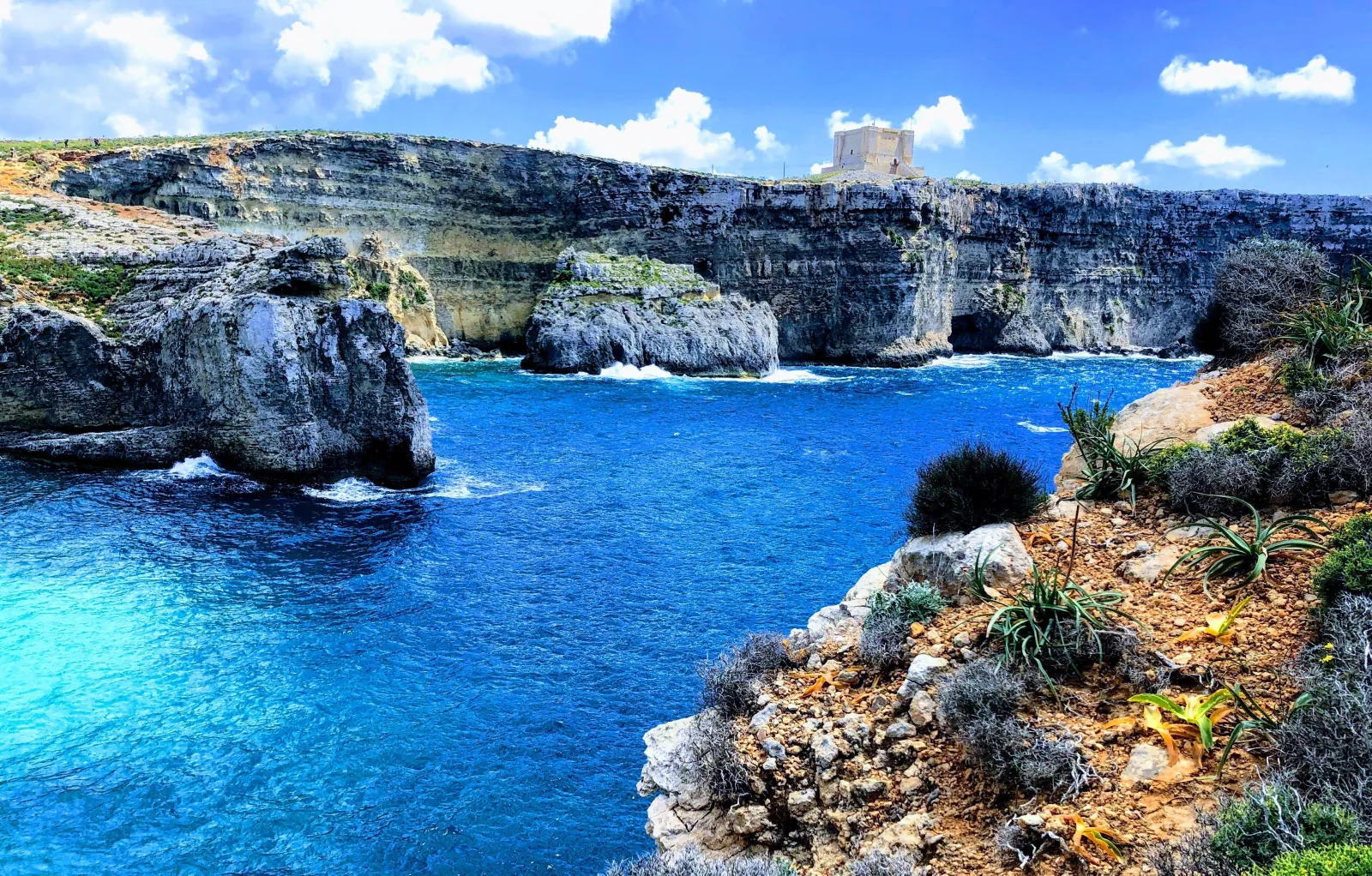 Sea caves and cliffs along the Comino coastline seen from the water