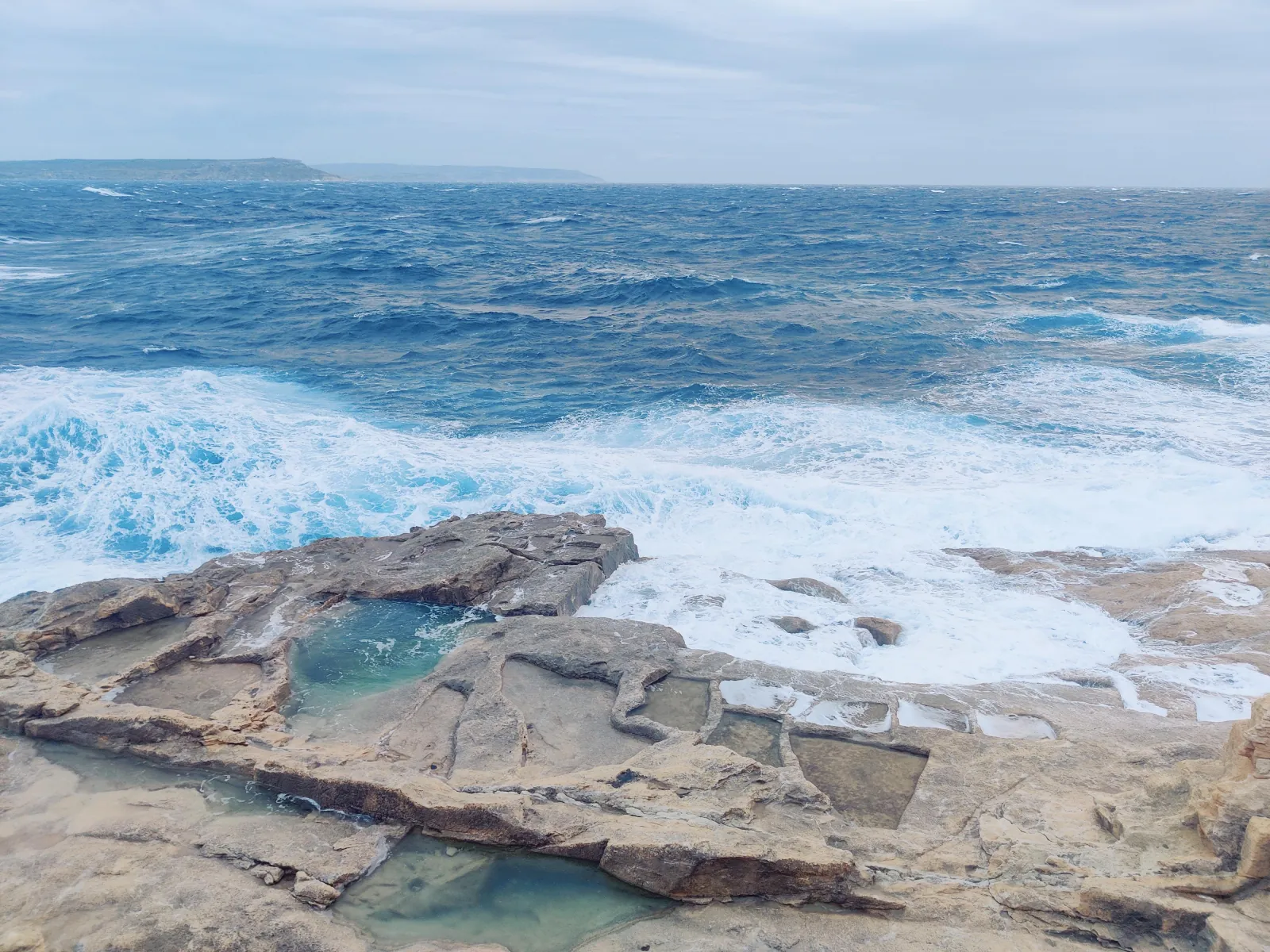Waves breaking over the flat coastal rock on Gozo