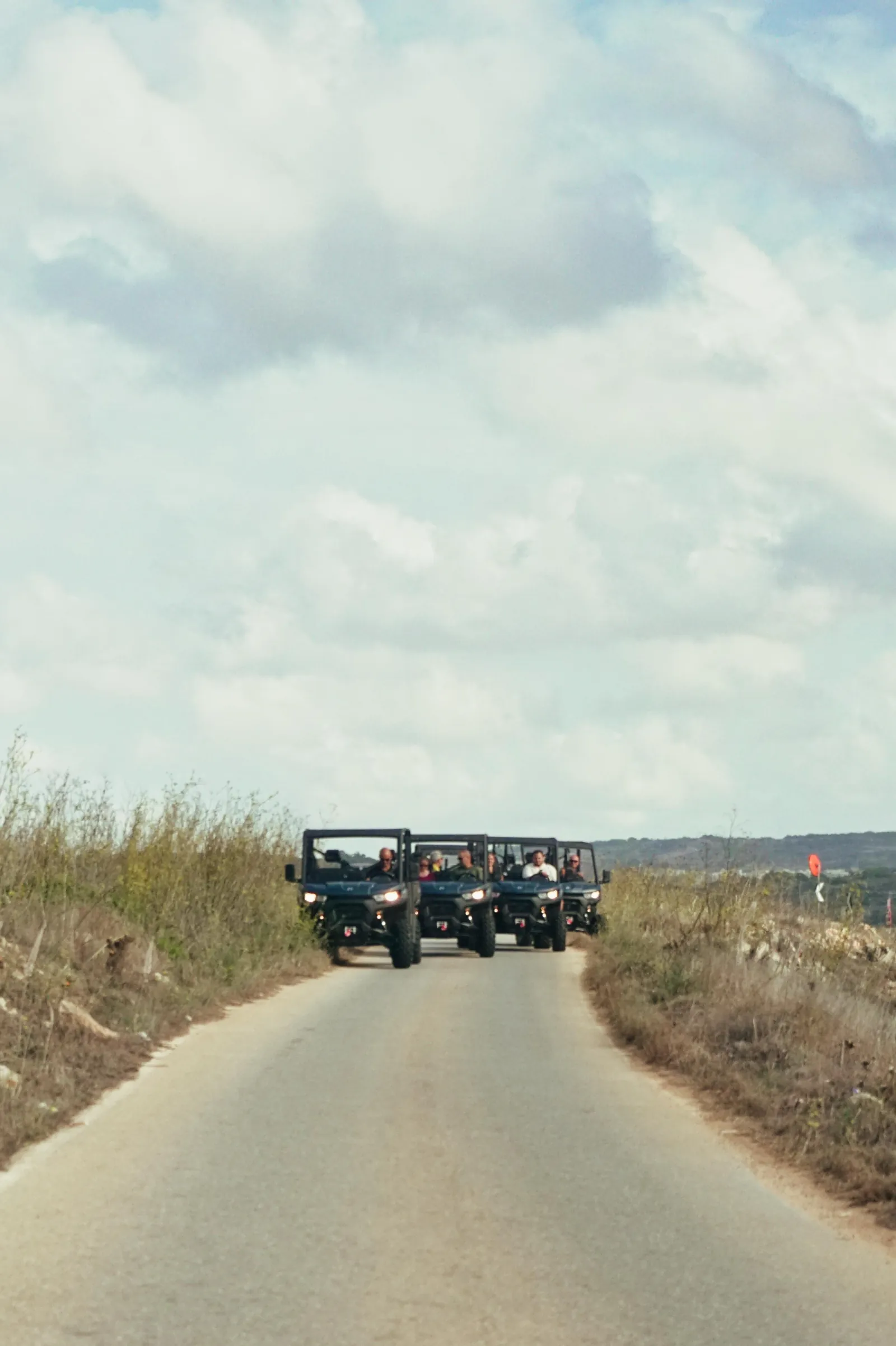 UTVs on a quiet Gozo country road under a pale evening sky