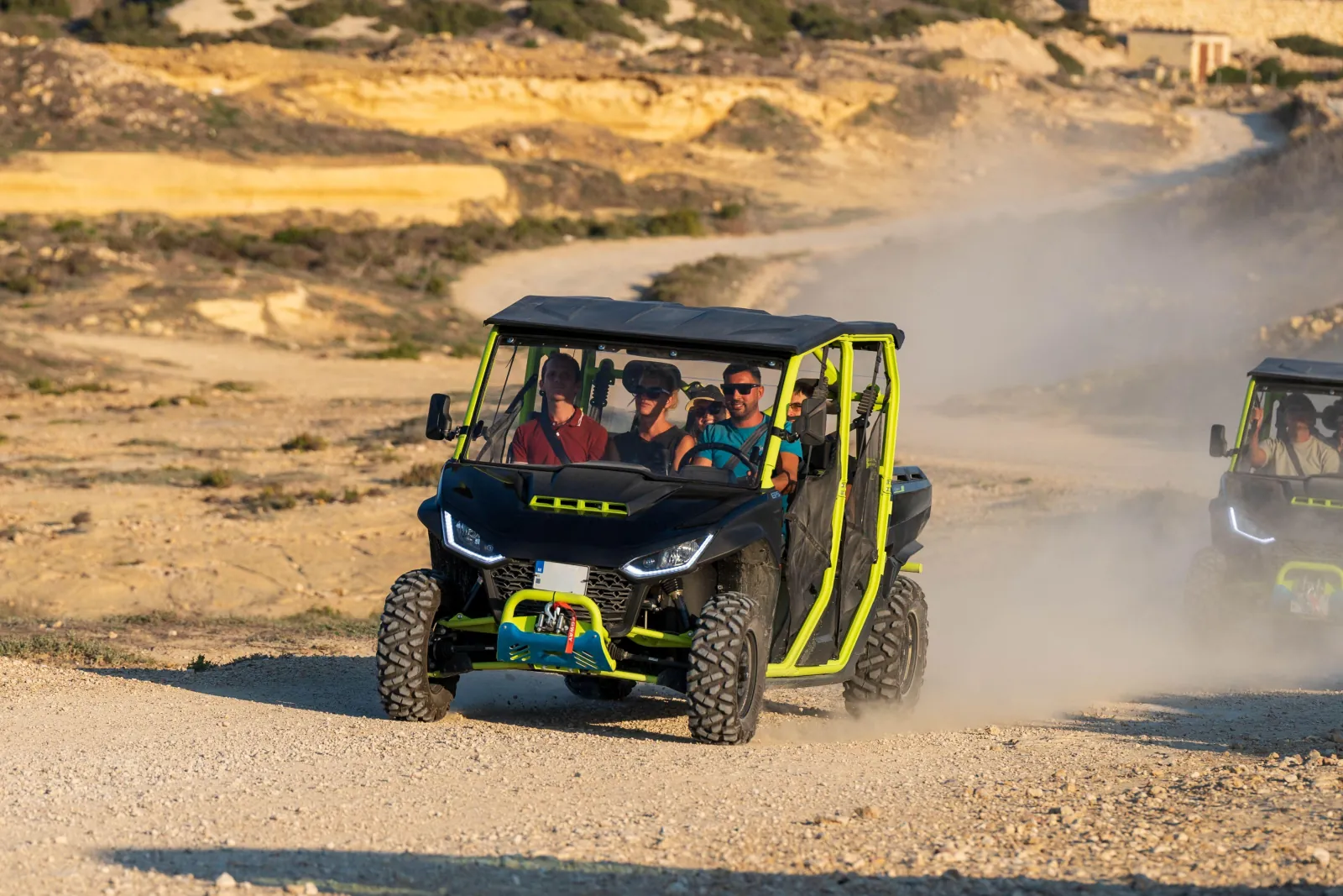 Open UTV raising dust on a dirt track above the Gozo coast